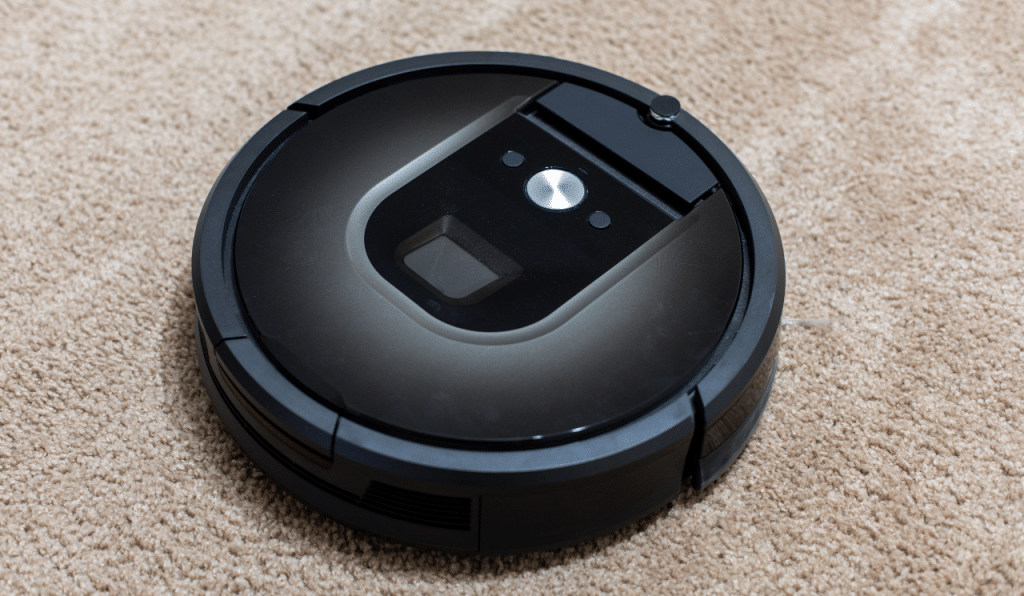 A black robotic vacuum, vacuuming on carpet.