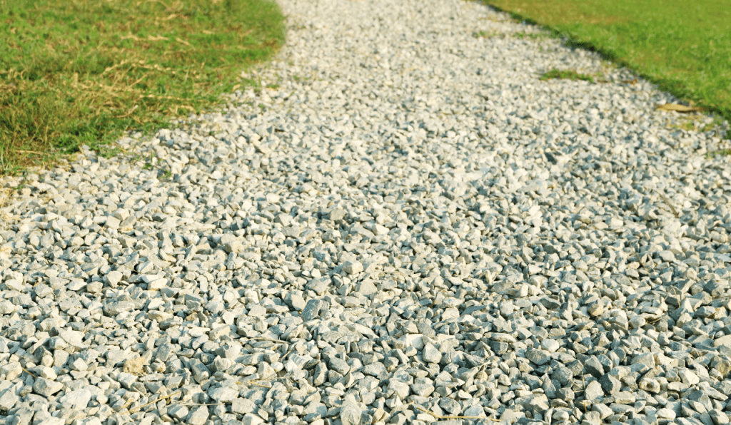 A gravel pathway leading to the front door of a home, with grass lawns on either side.