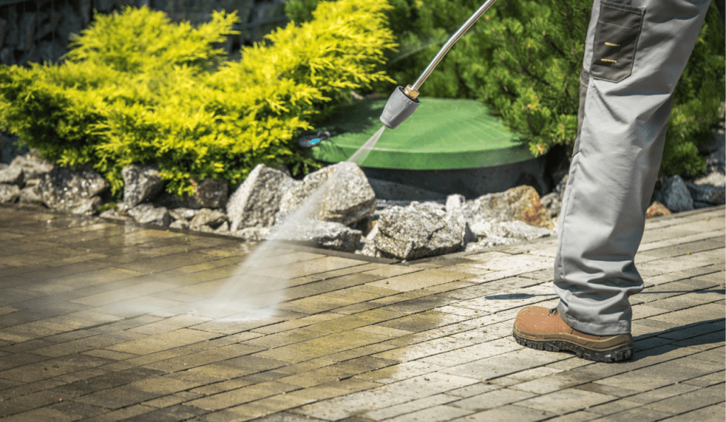 A man power washing a front garden path.