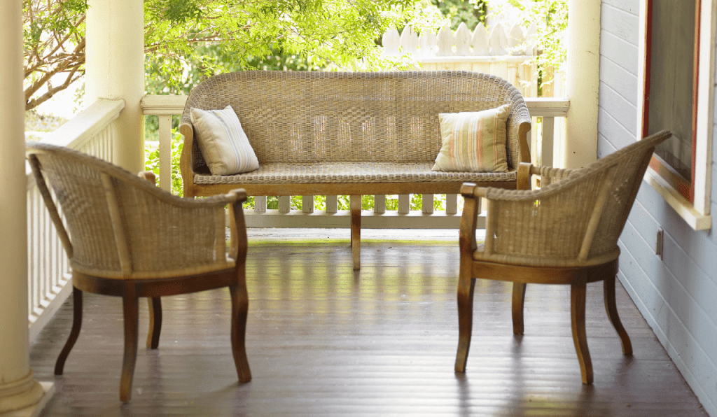 A set of weave furniture placed on an exterior porch.