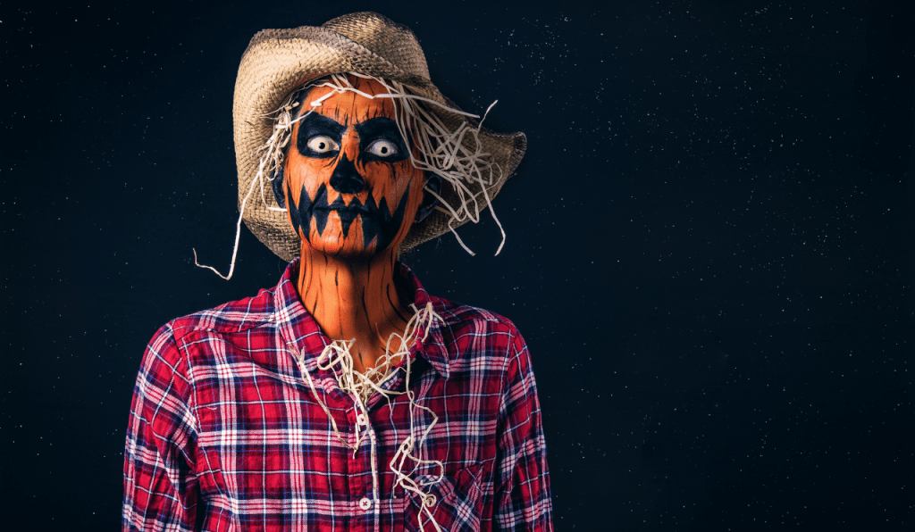 An adult dressed in a DIY Halloween costume pretending to be a scary scarecrow.